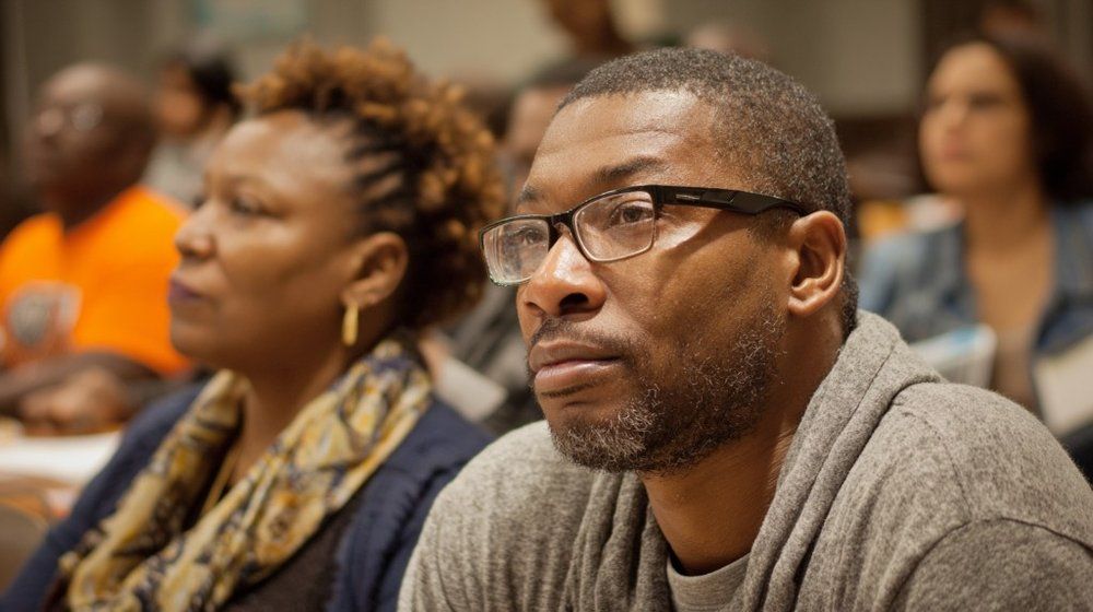 A community member attentively listening at a civil rights advocacy meeting